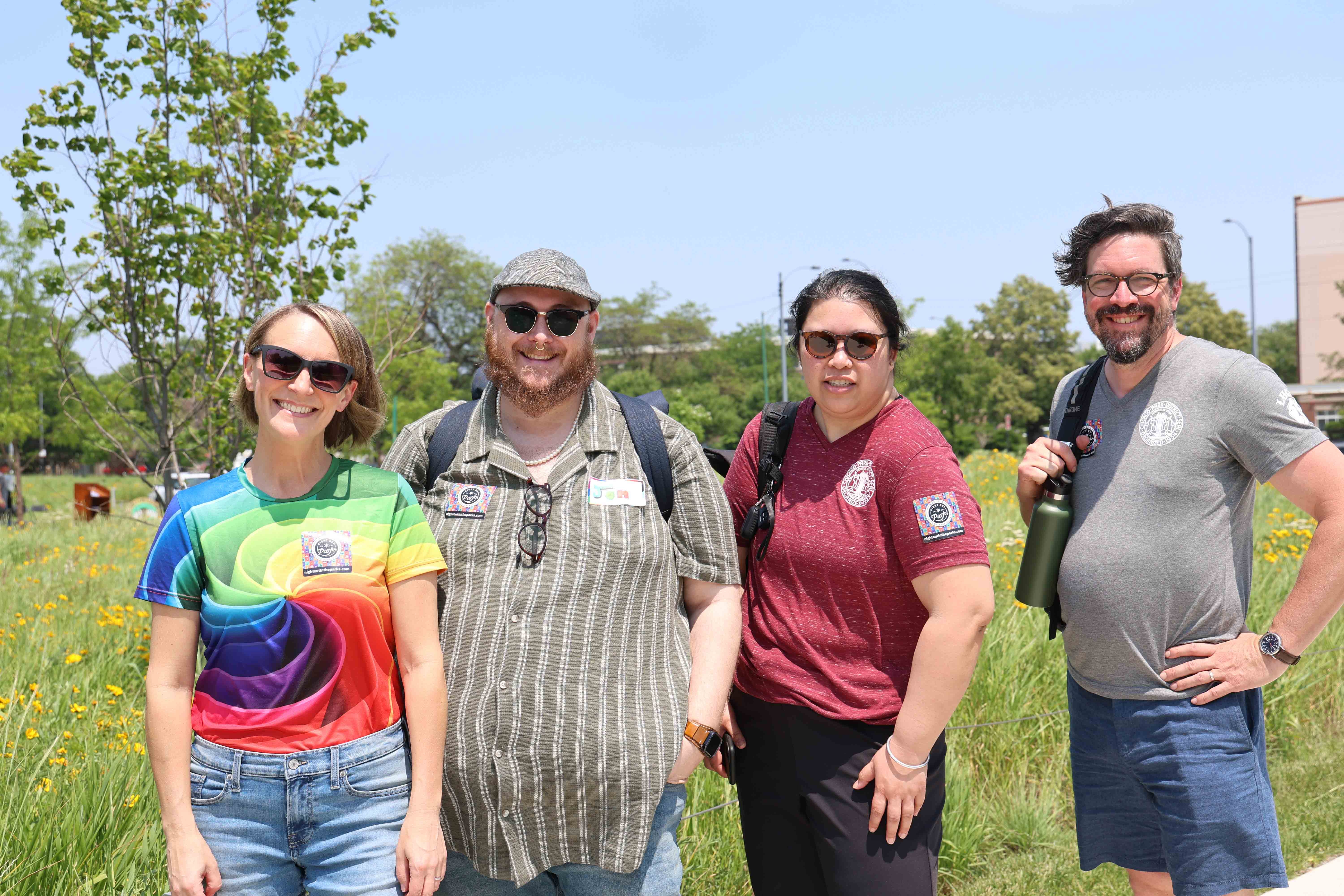 Four people smile for a photo on a sunny day in a park.